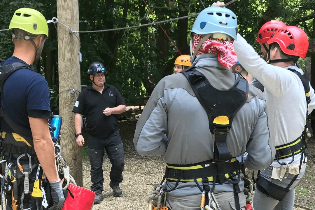 Team members on a high ropes course, harnessed and ready to inspect